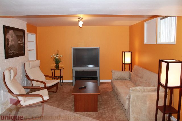 Living room with orange walls, modern furniture, and a flat-screen TV. - 2156 Cortell Ave, North Vancouver