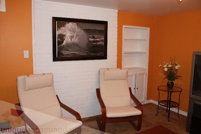 Furnished living room with orange walls, white brick accent wall, and modern furniture. - 2156 Cortell Ave, North Vancouver