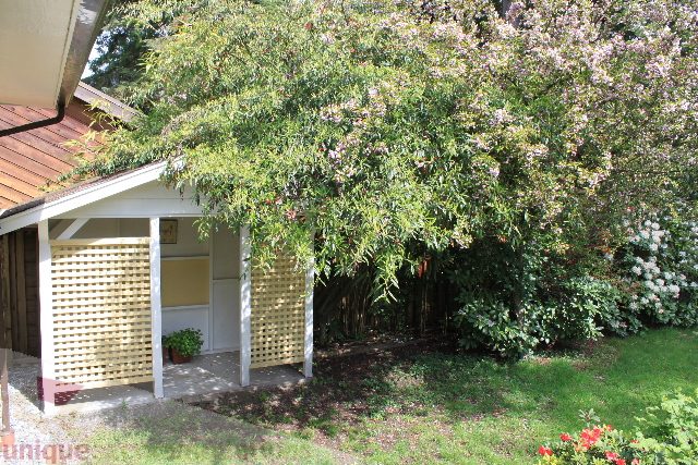 Furnished patio with lush greenery and blooming flowers. - 2156 Cortell Ave, North Vancouver