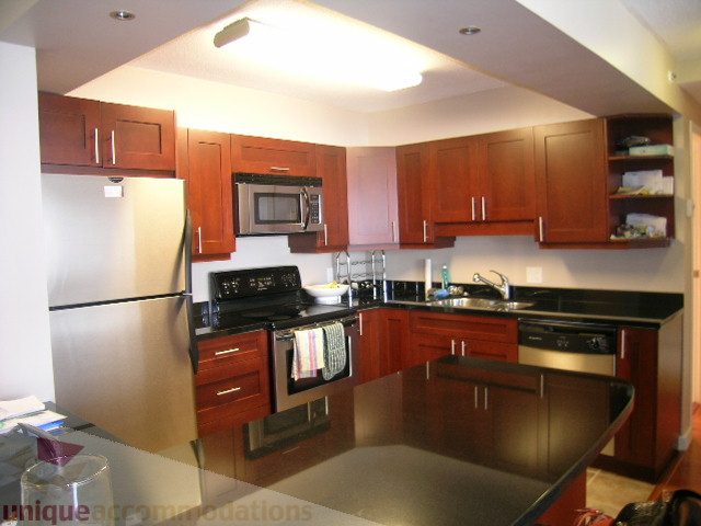 Bright kitchen with dark wood cabinets, stainless steel appliances, and granite countertops. - 2507 - 950 Cambie Street, Vancouver Downtown