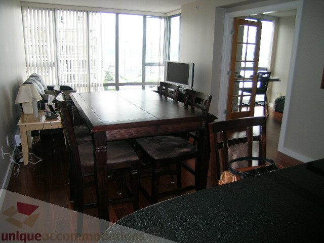 Dining area with large table, hardwood floors, and city view. - 2507 - 950 Cambie Street, Vancouver Downtown