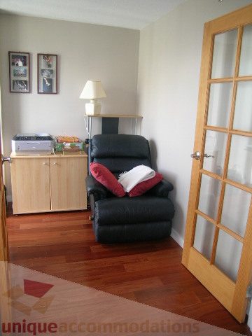 Furnished living room with hardwood floors and a black leather couch. - 2507 - 950 Cambie Street, Vancouver Downtown