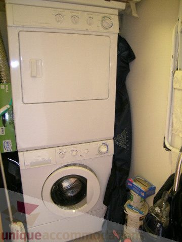Bright laundry room with stacked washer and dryer, small countertop, and storage items. - 2507 - 950 Cambie Street, Vancouver Downtown