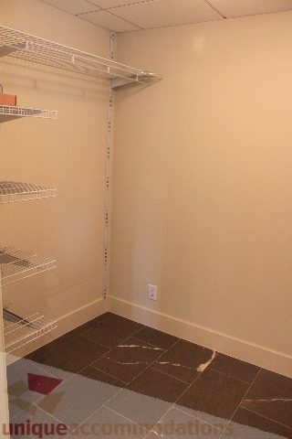 Spacious walk-in closet with white shelving and a brown mat. - 2205 - 1077 West Cordova, Vancouver Downtown