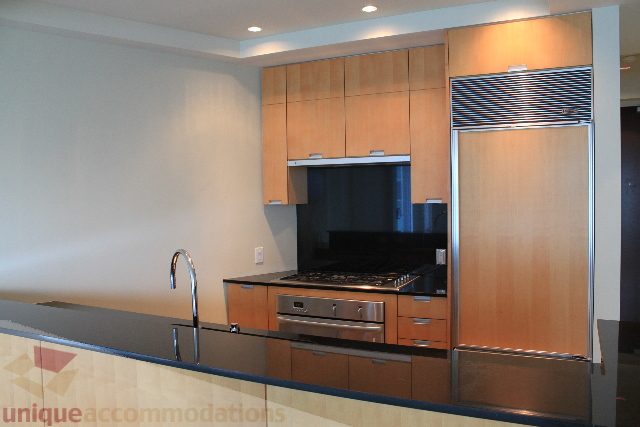 Bright kitchen with modern cabinetry, stainless steel appliances, and black countertops. - 2205 - 1077 West Cordova, Vancouver Downtown