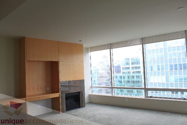 Spacious 1-bedroom condo with modern wood cabinets, large windows offering a stunning city view, and a cozy fireplace.