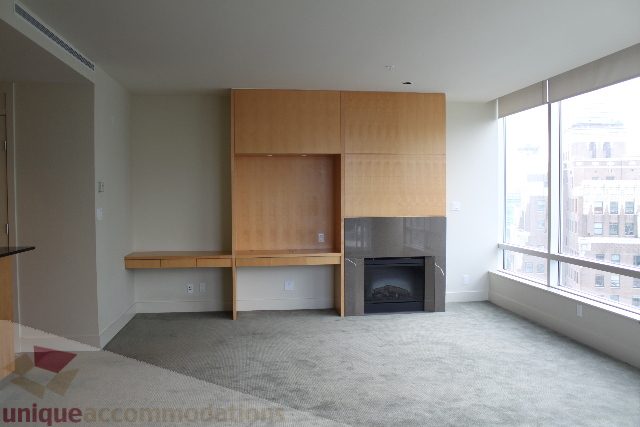 Spacious living room with wooden cabinets, city view, and modern fireplace. - 2205 - 1077 West Cordova, Vancouver Downtown