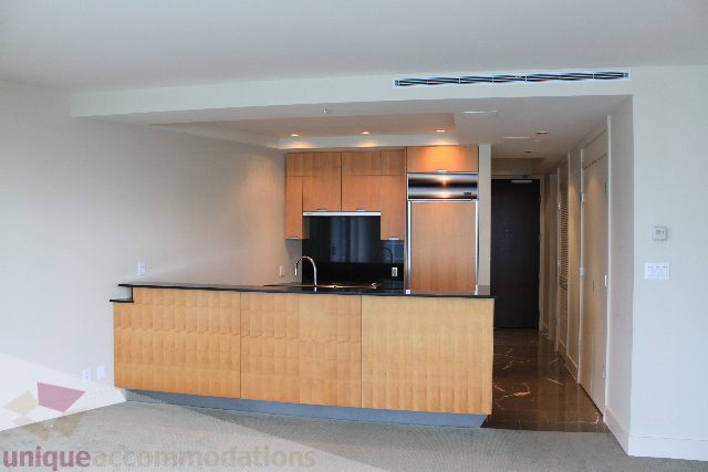 Modern kitchen with sleek black countertops and light wood cabinets. - 2205 - 1077 West Cordova, Vancouver Downtown