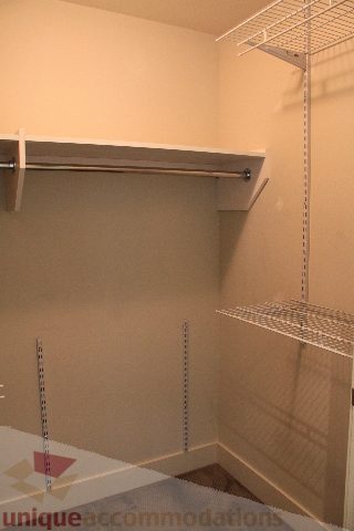 Spacious walk-in closet with white shelving and hanging rod, perfect for storage. - 2205 - 1077 West Cordova, Vancouver Downtown