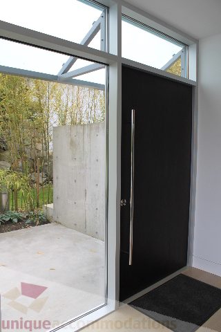 Modern entryway with glass doors and black door, leading to a serene outdoor patio. - 6012 Newton Wynd, Vancouver West Side