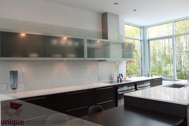 Bright kitchen with modern black and white cabinetry, large windows, and a view of greenery. - 6012 Newton Wynd, Vancouver West Side