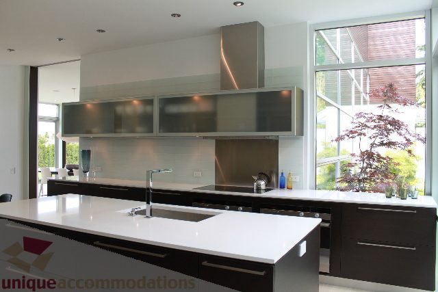 Bright kitchen with sleek white countertops and modern appliances, featuring large windows with a city view. - 6012 Newton Wynd, Vancouver West Side