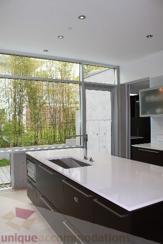 Bright kitchen with modern white countertops and large windows showcasing a city view. - 6012 Newton Wynd, Vancouver West Side