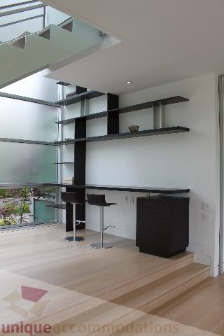 Modern living room with sleek black shelves and hardwood floors, featuring a city view. - 6012 Newton Wynd, Vancouver West Side