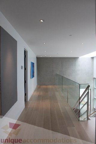 Foyer with wooden floors, glass railing, and concrete wall. - 6012 Newton Wynd, Vancouver West Side