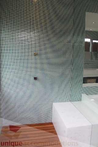 Modern bathroom with mosaic tile walls and white countertop. - 6012 Newton Wynd, Vancouver West Side