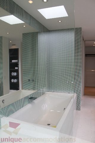 Modern bathroom with glass shower, mosaic tiles, and skylight. - 6012 Newton Wynd, Vancouver West Side