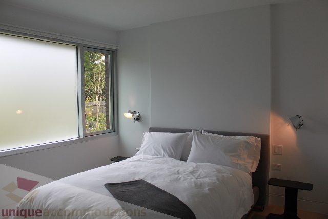 Bright bedroom with large window and cozy bedding. - 6012 Newton Wynd, Vancouver West Side