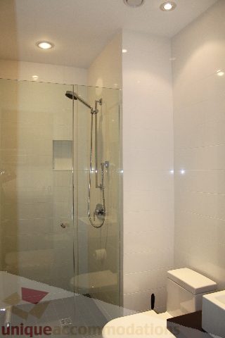 Modern bathroom with glass shower and sleek white tiles. - 6012 Newton Wynd, Vancouver West Side