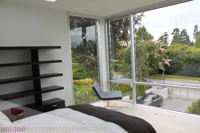 Spacious bedroom with large windows overlooking lush greenery. - 6012 Newton Wynd, Vancouver West Side