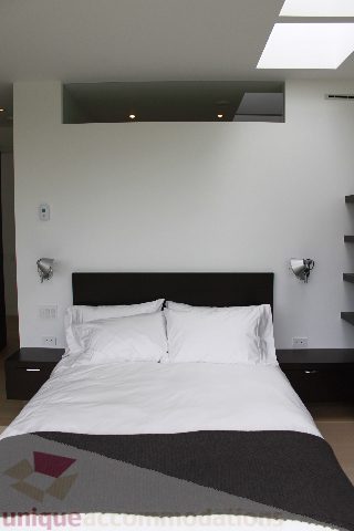 Spacious bedroom with modern headboard and wall-mounted lights. - 6012 Newton Wynd, Vancouver West Side
