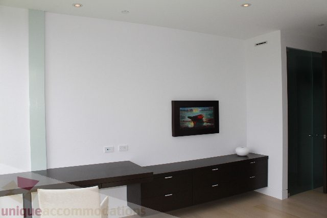Modern living room with minimalist decor, dark wood furniture, and a large wall art piece. - 6012 Newton Wynd, Vancouver West Side