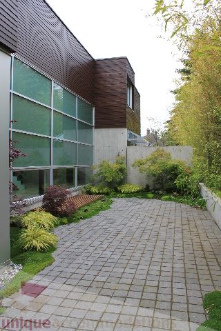 Furnished patio with modern glass wall and stone pathway leading to house. - 6012 Newton Wynd, Vancouver West Side