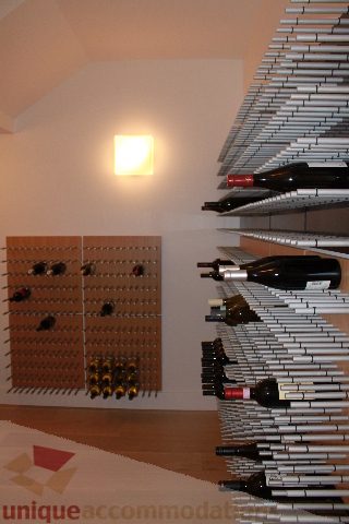 Wine cellar with pegboard racks and bottles, hardwood floors. - 6012 Newton Wynd, Vancouver West Side