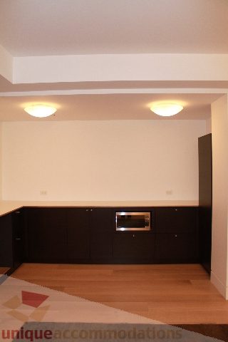 Bright kitchen with black cabinets, light wood floors, and modern lighting. - 6012 Newton Wynd, Vancouver West Side