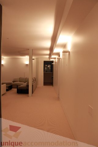 Furnished hallway leading to a cozy living area with plush seating and warm lighting. - 6012 Newton Wynd, Vancouver West Side