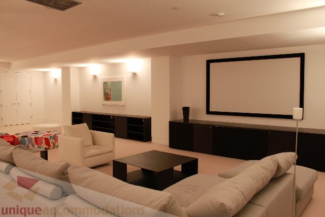 Furnished living room with modern furniture and large screen for entertainment. - 6012 Newton Wynd, Vancouver West Side