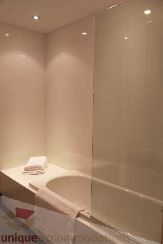 Furnished bathroom with a bathtub and neatly folded towels on the counter. - 6012 Newton Wynd, Vancouver West Side