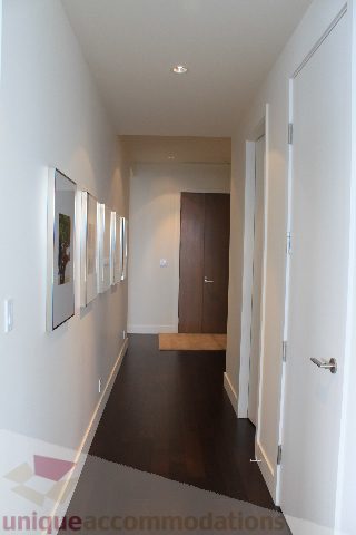 Furnished hallway with dark wood flooring and framed artwork on the wall. - 6002 - 1128 West Georgia, Vancouver Downtown