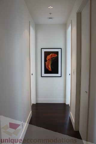 Furnished hallway with dark wood flooring and a framed floral artwork. - 6002 - 1128 West Georgia, Vancouver Downtown