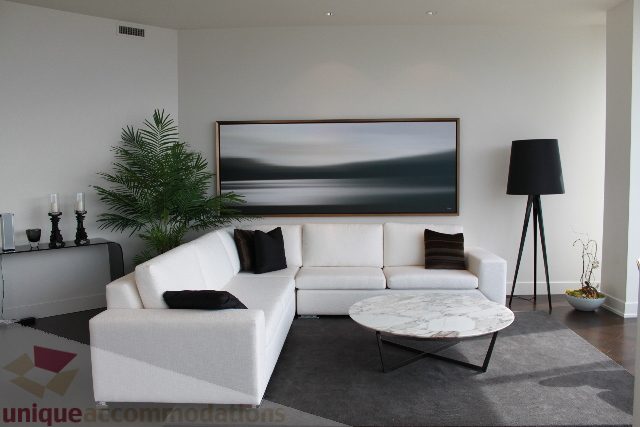 Bright living room with modern white furniture, large abstract art, and a sleek black lamp. - 6002 - 1128 West Georgia, Vancouver Downtown