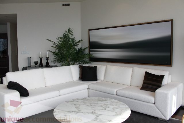 Bright living room with white sectional sofa, large abstract art, and potted plant. - 6002 - 1128 West Georgia, Vancouver Downtown