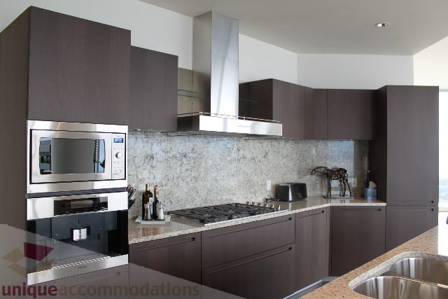 Modern kitchen with dark wood cabinets, stainless steel appliances, and granite countertops. - 6002 - 1128 West Georgia, Vancouver Downtown