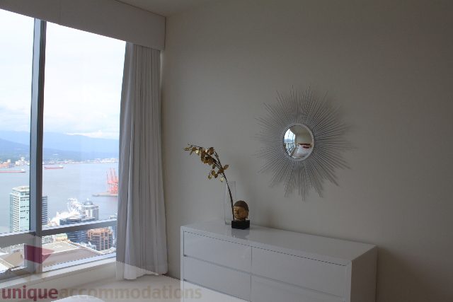 Bright living room with city view and sunburst mirror. - 6002 - 1128 West Georgia, Vancouver Downtown