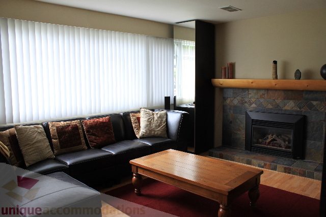 Furnished living room with a cozy fireplace and large windows. - 2730 Ailsa Crescent, North Vancouver
