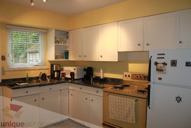 Bright kitchen with white cabinets, granite countertops, and a window view. - 2730 Ailsa Crescent, North Vancouver