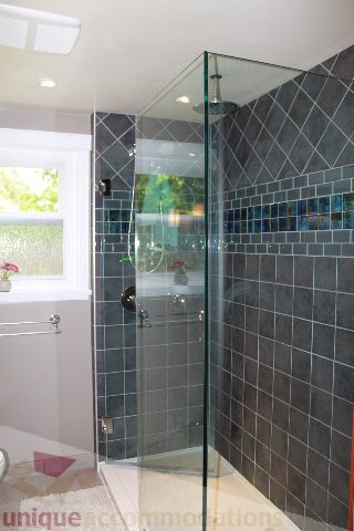 Bright bathroom with glass shower and dark tile walls. - 2730 Ailsa Crescent, North Vancouver