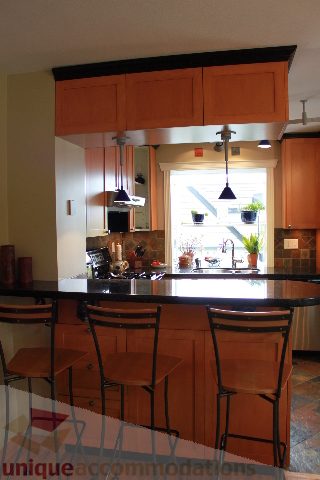 Bright kitchen with wooden cabinets, black countertops, and a city view through the window. - 2730 Ailsa Crescent, North Vancouver