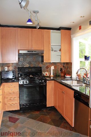 Bright kitchen with wooden cabinets, granite countertops, and a black stove. - 2730 Ailsa Crescent, North Vancouver