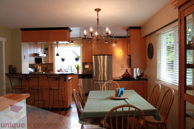 Bright kitchen with wooden cabinets, stainless steel appliances, and a chandelier. - 2730 Ailsa Crescent, North Vancouver