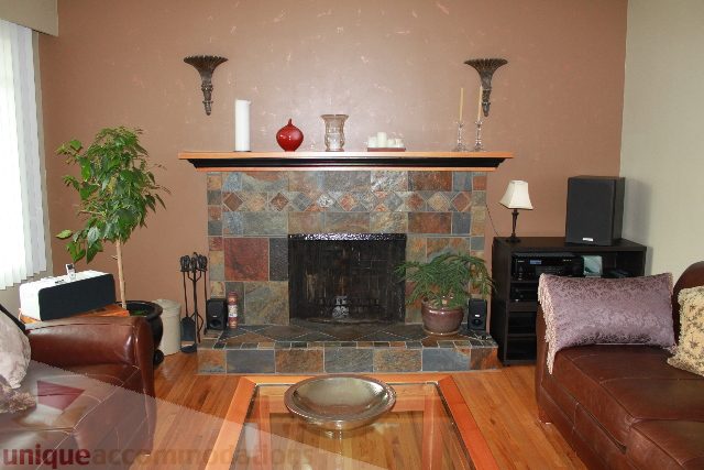 Furnished living room with hardwood floors and a stone fireplace. - 2730 Ailsa Crescent, North Vancouver