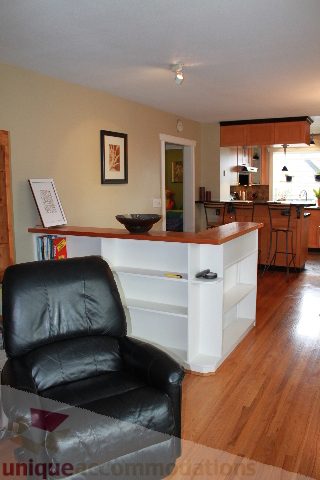 Bright living room with black leather chair and hardwood floors. - 2730 Ailsa Crescent, North Vancouver