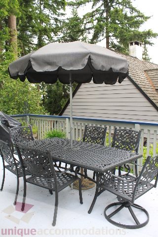 Furnished patio with outdoor furniture and umbrella, surrounded by trees. - 2730 Ailsa Crescent, North Vancouver