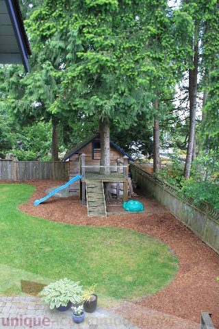 Playful backyard with a wooden playhouse and mulch path. - 2730 Ailsa Crescent, North Vancouver
