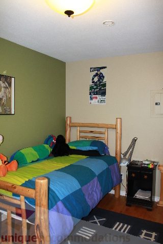 Bright bedroom with wooden bunk beds, colorful bedding, and a poster on the wall. - 2730 Ailsa Crescent, North Vancouver