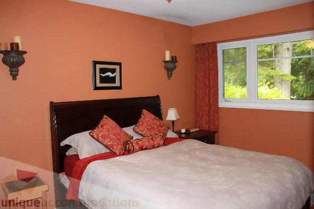Furnished bedroom with orange walls, patterned curtains, and a cozy bed setup. - 2730 Ailsa Crescent, North Vancouver